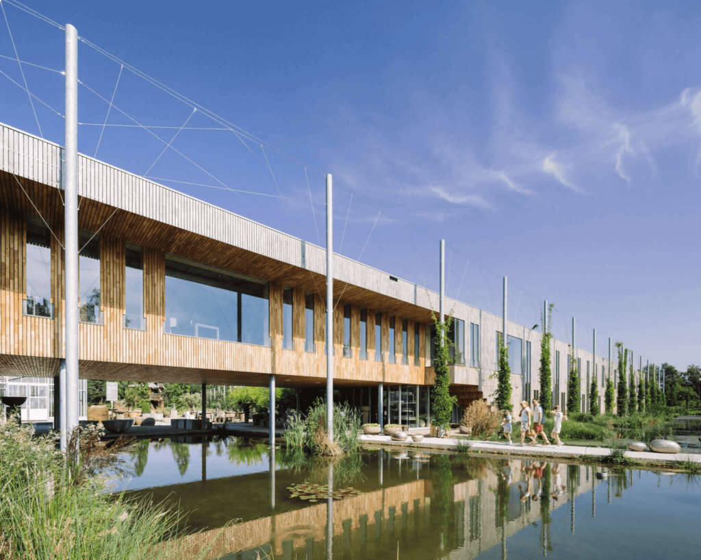 Duurzaam gebouw met vijver en wandelpad.
