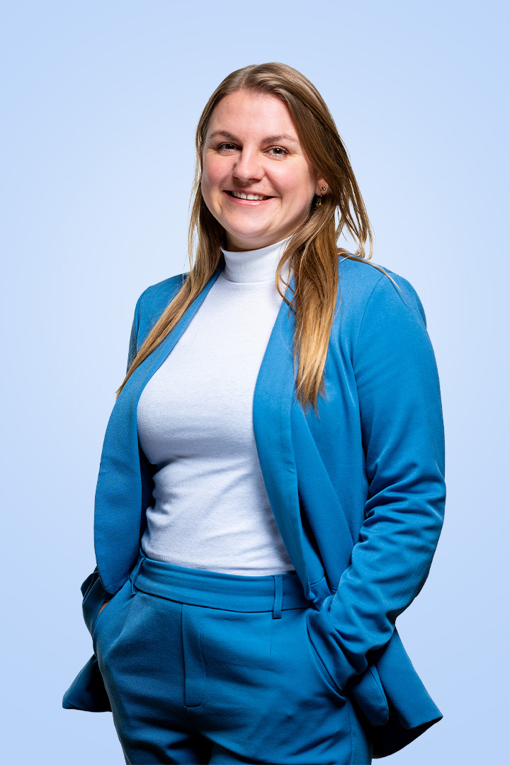 Vrouw in blauw pak glimlacht naar camera.