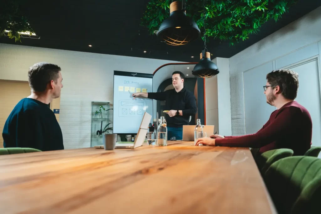 Man presenteert aan collega's in vergaderruimte.