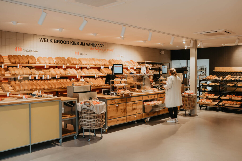Klanten kiezen brood in moderne bakkerij.