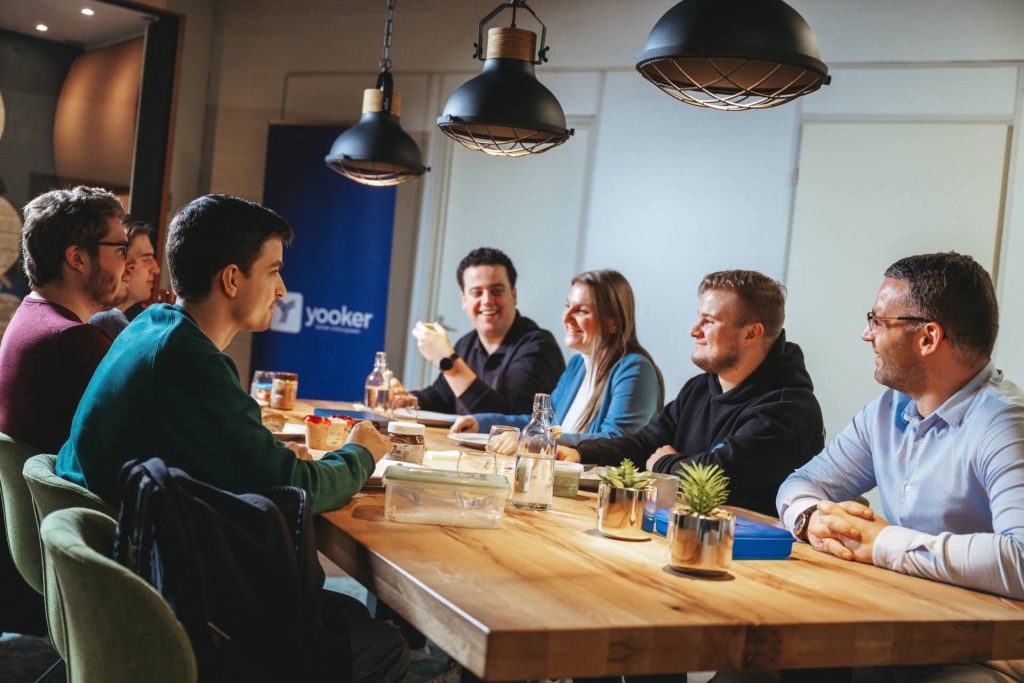 Groep mensen vergadert rond tafel in kantoor.