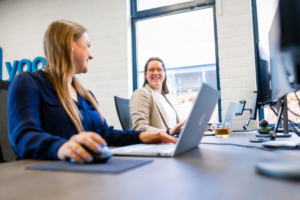 Twee vrouwen werken samen op kantoor met laptops.