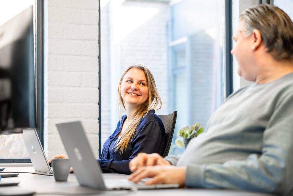 Collega's werken samen op kantoor met laptops.
