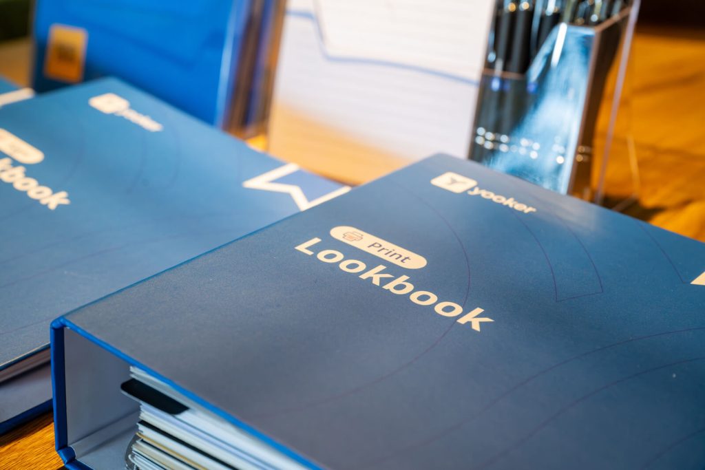 Blauwe lookbook mappen op tafel met pennenhouder